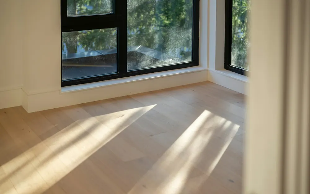 窓から差す日が、木の床に伸びる空の部屋。住まいの分け方を考える章の写真